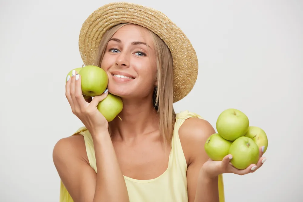kobieta trzyma kilka zielonych jabłek